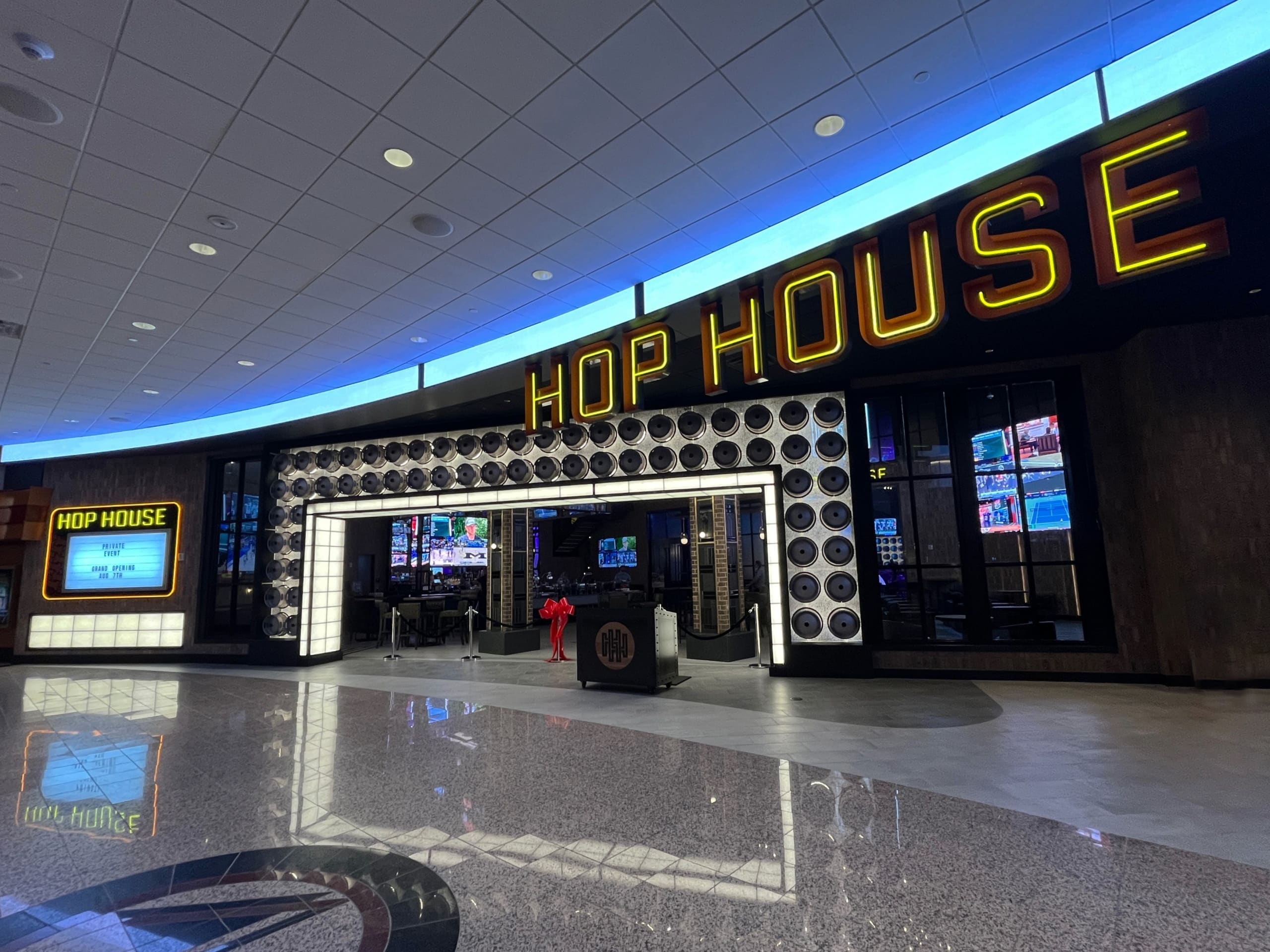 promenade entrance into Hop House sports bar with a archway of glowing kegs and bold, lit overhead signage